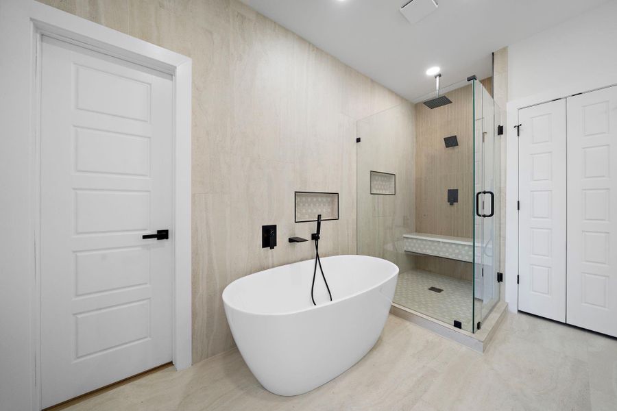 This modern primary bathroom features a sleek freestanding tub, a spacious glass-enclosed shower with a bench, and elegant tile work. The space is bright and minimalist, offering a luxurious and relaxing atmosphere. This modern primary bathroom features a sleek freestanding tub, a spacious glass-enclosed shower with a bench, and elegant tile work. The space is bright and minimalist, offering a luxurious and relaxing atmosphere.