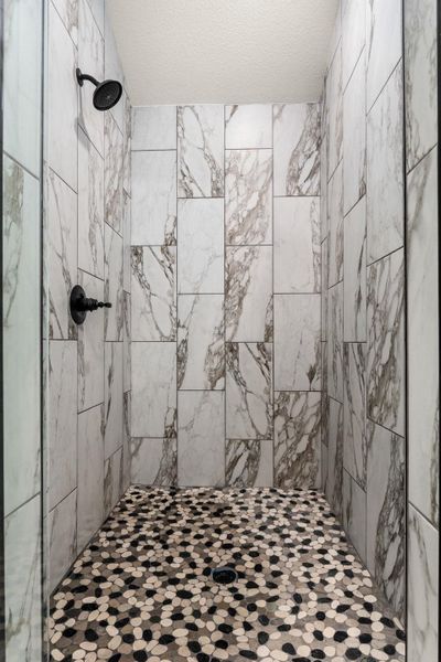 Bathroom featuring a shower stall and a textured ceiling