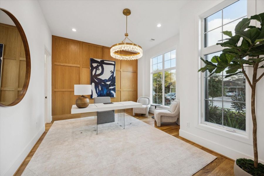 Custom millwork and warm white oak paneling define a dedicated first floor study designed for focus and flexibility. Natural light from oversized windows, a full bath nearby, and generous wall space allow the room to function equally well as a home office, creative studio, or private guest suite. Custom millwork and warm white oak paneling define a dedicated first floor study designed for focus and flexibility. Natural light from oversized windows, a full bath nearby, and generous wall space allow the room to function equally well as a home office, creative studio, or private guest suite.