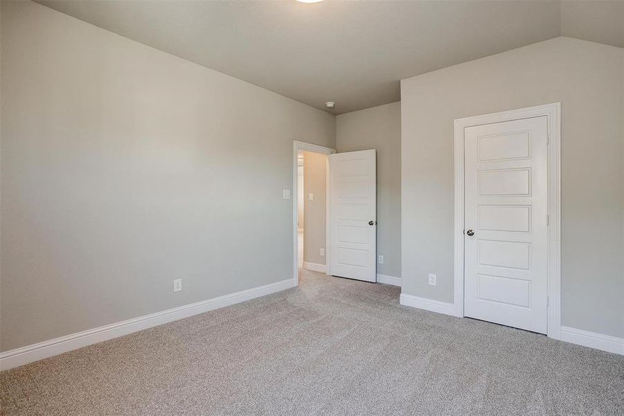 Unfurnished bedroom featuring lofted ceiling, light carpet, and a closet