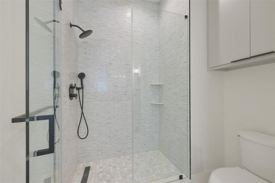 A view of one of the secondary bedroom's showers with linear drain and frameless glass door.