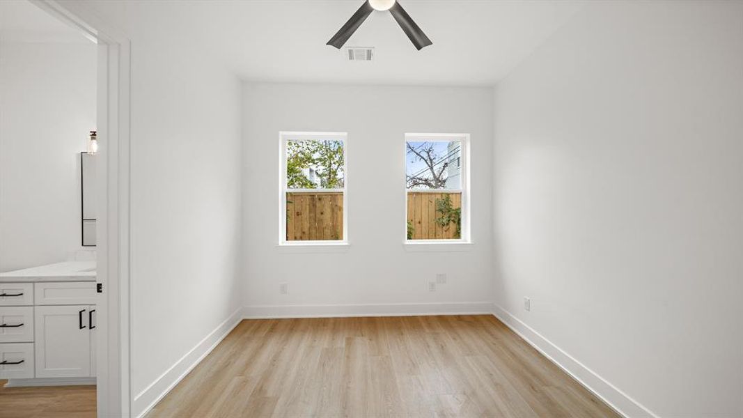 Beautiful secondary bedroom with luxury vinyl plank floors, a ceiling fan, and a complete en-suite bathroom.