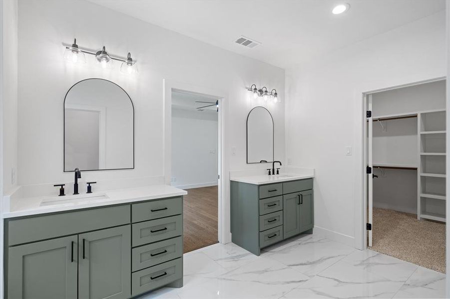 Bathroom featuring two vanities, a spacious closet, recessed lighting, and light marble finish flooring Bathroom featuring two vanities, a spacious closet, recessed lighting, and light marble finish flooring