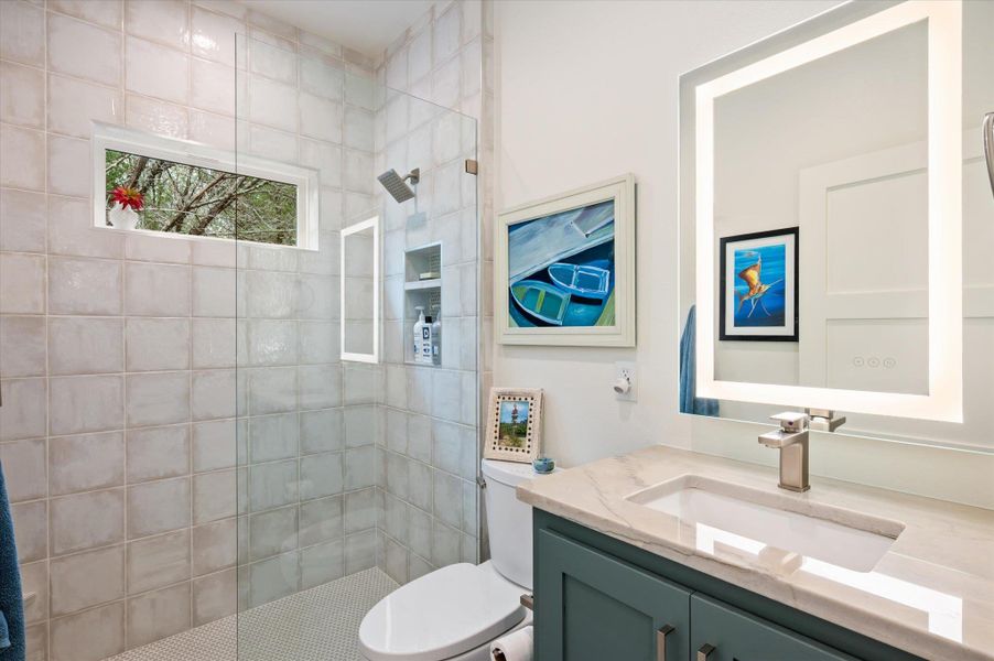 Secondary bathroom with natural stone counter, tasteful tile, lighted bathroom mirrow, floating custom cabinet with slow close door/drawer