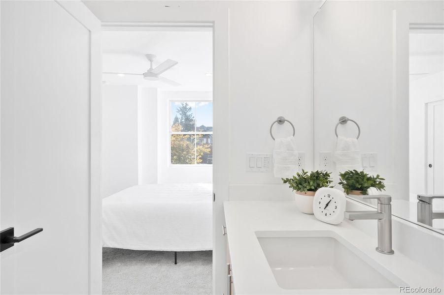 The light-filled en suite bath features modern fixtures and flows seamlessly into the bedroom.