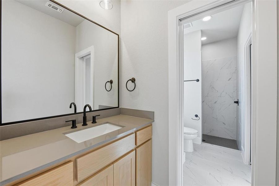 Bathroom featuring a marble finish shower, vanity, and light marble finish floors