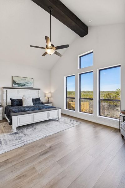 Primary bedroom set towards the back of the home with beamed ceiling and picture windows