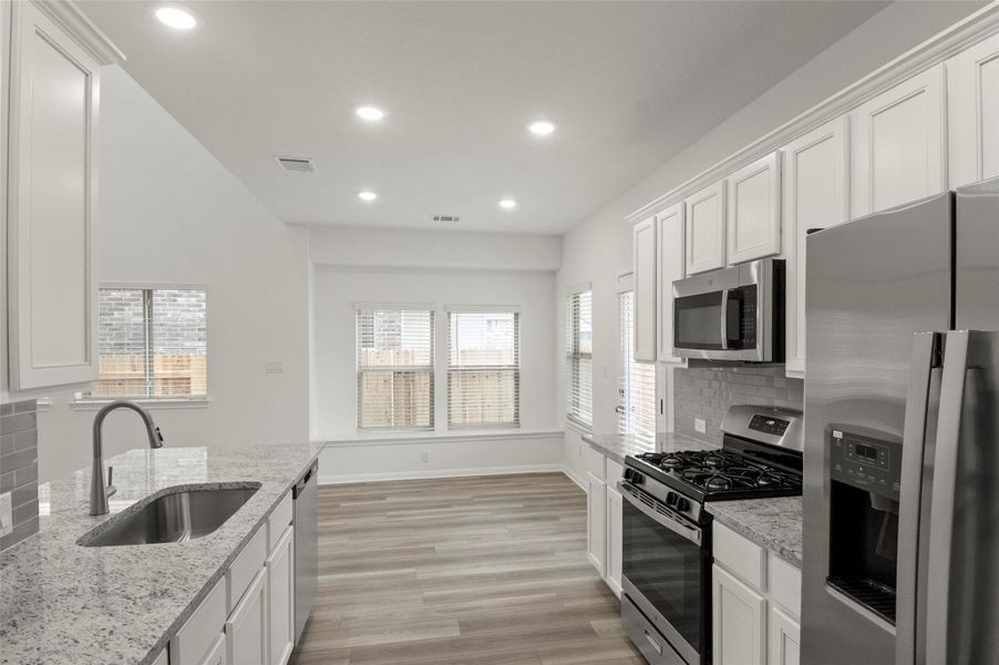 Kitchen with stainless steel appliances, backsplash, healthy amount of natural light, white cabinets, and recessed lighting Kitchen with stainless steel appliances, backsplash, healthy amount of natural light, white cabinets, and recessed lighting