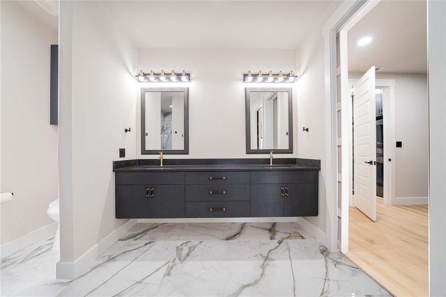 Dual floating vanity with dark cabinetry, gold-tone hardware, and integrated sinks