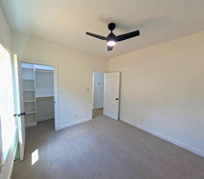 Unfurnished bedroom with carpet flooring, a spacious closet, and ceiling fan Unfurnished bedroom with carpet flooring, a spacious closet, and ceiling fan