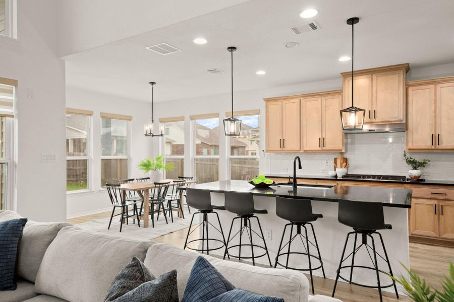 The kitchen boasts a large center island lined with bar seating, along with sleek black quartz countertops and black fixtures, SS appliances, and more! The kitchen boasts a large center island lined with bar seating, along with sleek black quartz countertops and black fixtures, SS appliances, and more!