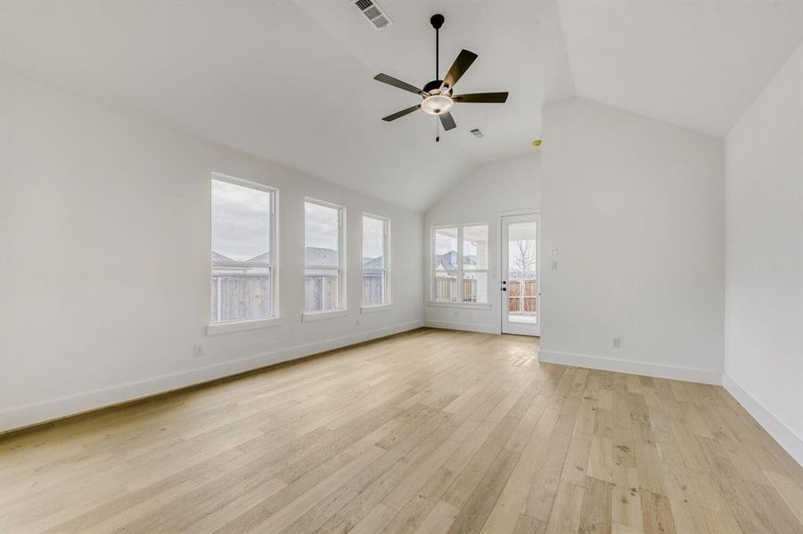 Unfurnished living room featuring light wood finished floors, a ceiling fan, and a high ceiling Unfurnished living room featuring light wood finished floors, a ceiling fan, and a high ceiling