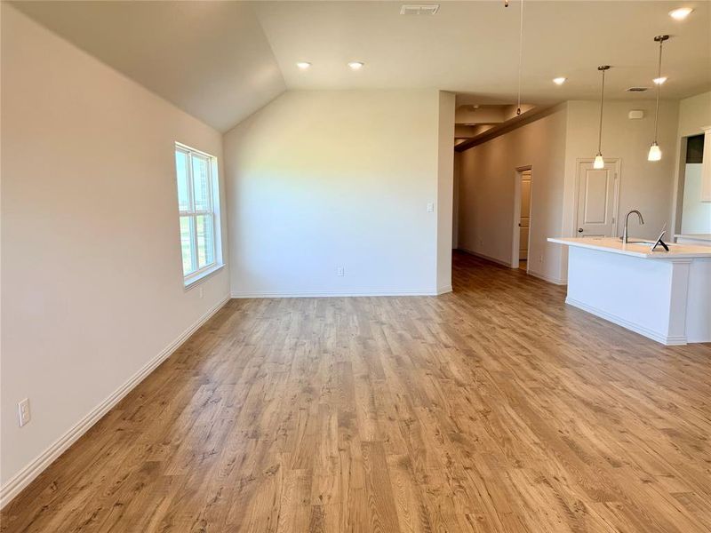 Open-concept living space featuring wood-finish flooring, vaulted ceilings, and recessed lighting