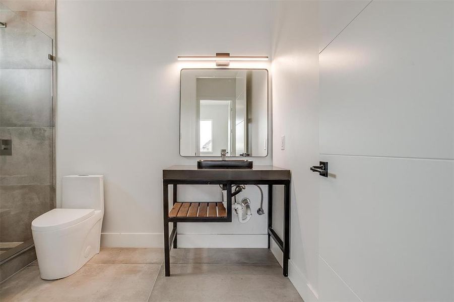 Full bathroom with concrete flooring, toilet, vanity, baseboards, and a shower stall