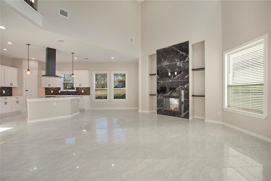 Unfurnished living room with a towering ceiling and a fireplace