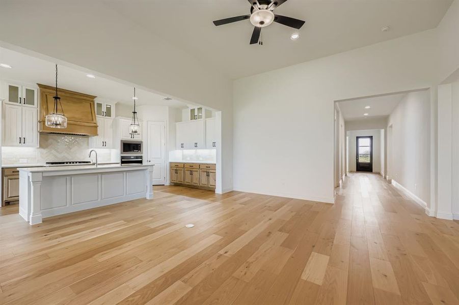 Kitchen featuring recessed lighting, open floor plan, decorative backsplash, an island with sink, and decorative light fixtures