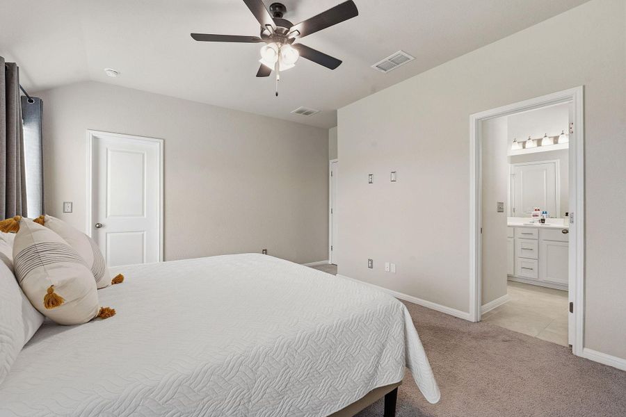 Bedroom with light colored carpet, a ceiling fan, vaulted ceiling, and ensuite bathroom Bedroom with light colored carpet, a ceiling fan, vaulted ceiling, and ensuite bathroom