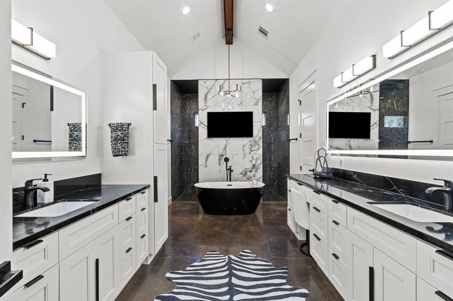 A bright vaulted ceiling primary bath with a vanity area, double sided sink areas, and separate soaking tub from the drive-thru shower.