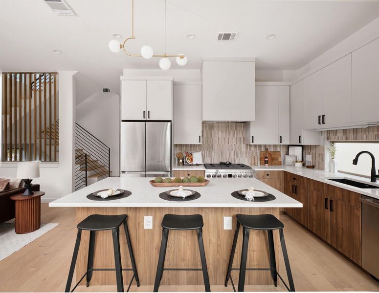 Kitchen with a breakfast bar area, appliances with stainless steel finishes, white cabinetry, light wood-type flooring, and recessed lighting
