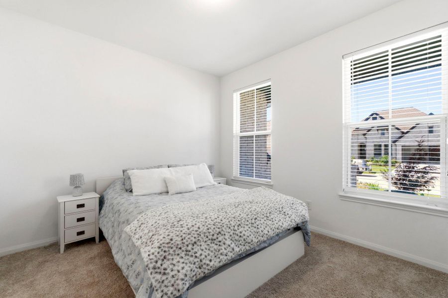 Bright and cozy bedroom with carpeted floor, white walls, and two large windows offering plenty of natural light. Ideal for a peaceful retreat.