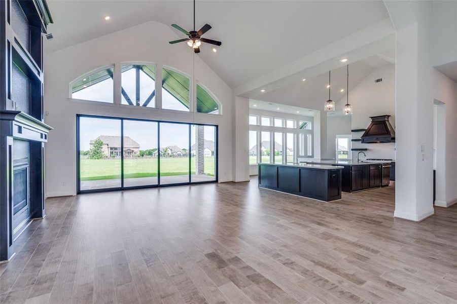 Unfurnished living room featuring high vaulted ceiling, ceiling fan, a healthy amount of sunlight, and light wood-type flooring