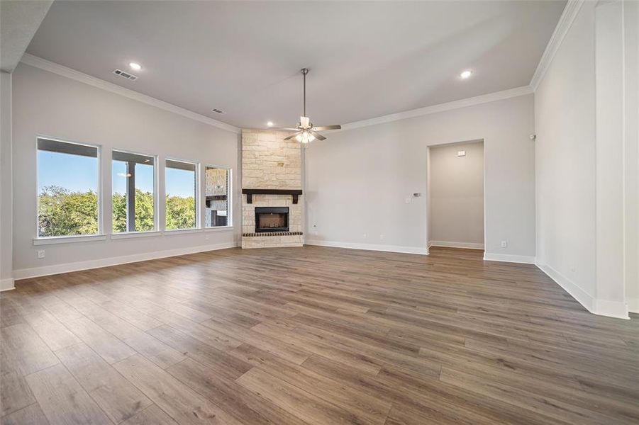 Unfurnished living room with crown molding, ceiling fan, a fireplace, wood finished floors, and recessed lighting Unfurnished living room with crown molding, ceiling fan, a fireplace, wood finished floors, and recessed lighting
