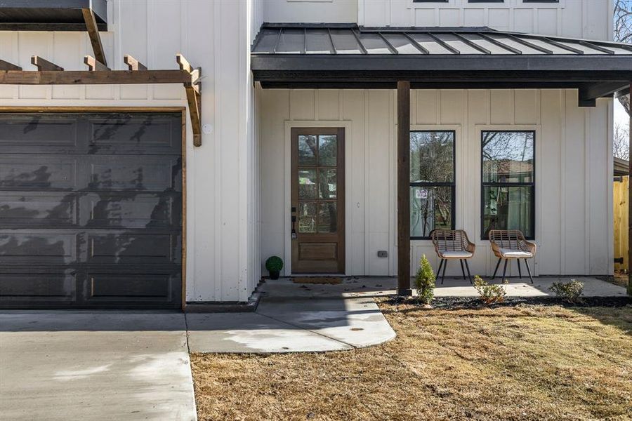 View of exterior entry featuring metal roof, a standing seam roof, concrete driveway, and board and batten siding