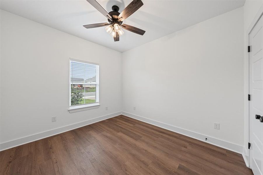 This room features a ceiling fan with integrated lighting, a window with blinds, and rich wood-style flooring