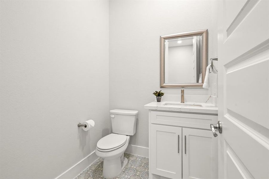 The Powder Room, located off the Garage and Mud Room, boasts chic tiling, a built-in vanity, quartz countertop, undermount sink, and custom framed mirror.