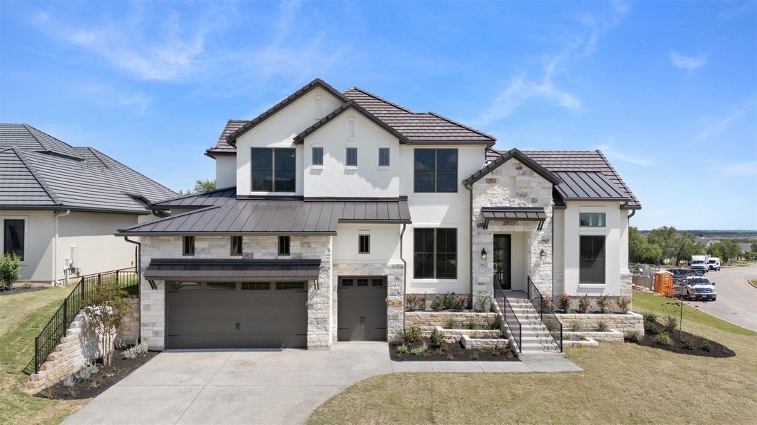 Architectural splendor with a blend of stone and stucco, featuring a prominent two-car garage and manicured front yard.