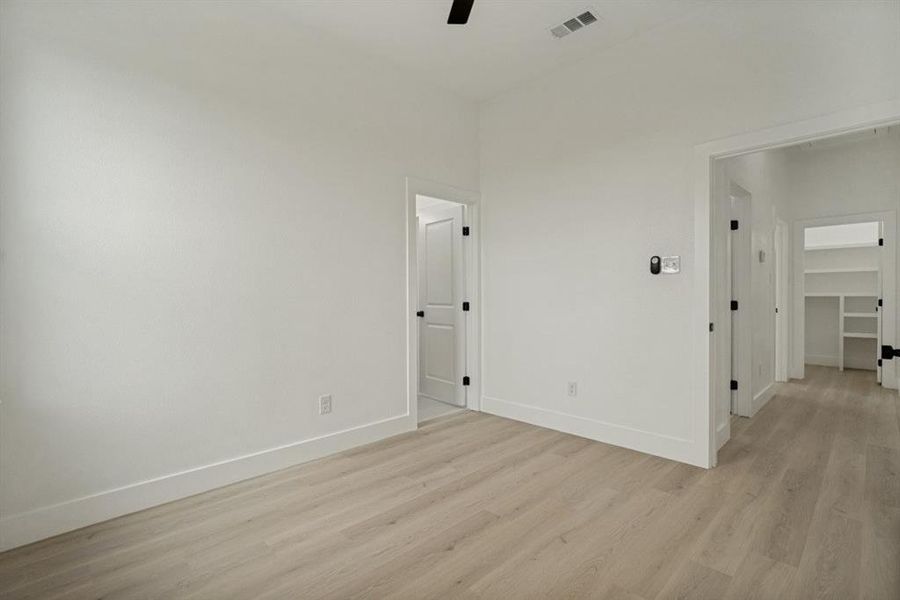 Spacious room featuring light wood-finish flooring, white walls, and bright white trim Spacious room featuring light wood-finish flooring, white walls, and bright white trim