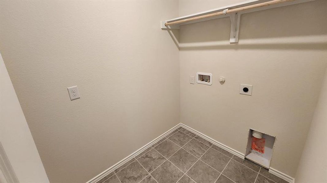 Dedicated laundry area featuring a shelf with a hanging rod, tile flooring, and utility hookups Dedicated laundry area featuring a shelf with a hanging rod, tile flooring, and utility hookups