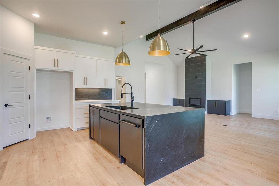 Kitchen featuring white cabinetry, light hardwood / wood-style flooring, a kitchen island with sink, sink, and tasteful backsplash