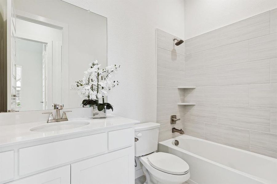 Full bathroom featuring tiled shower / bath, vanity, and toilet