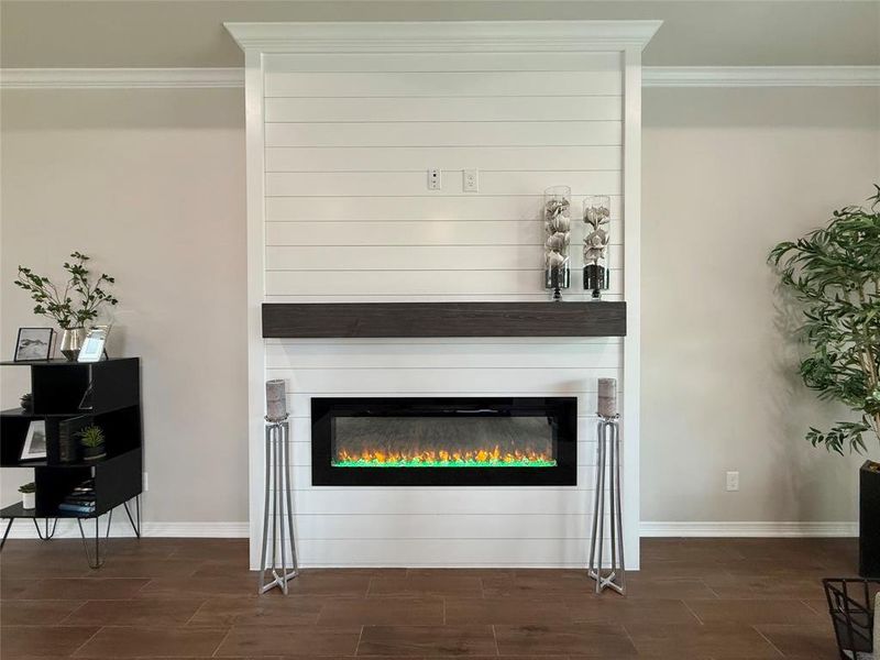 Detailed view of crown molding, wood finish floors, and a fireplace Detailed view of crown molding, wood finish floors, and a fireplace