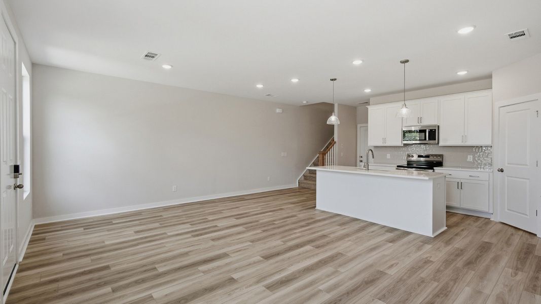 Kitchen with island and pantry door next to entryway and stairs