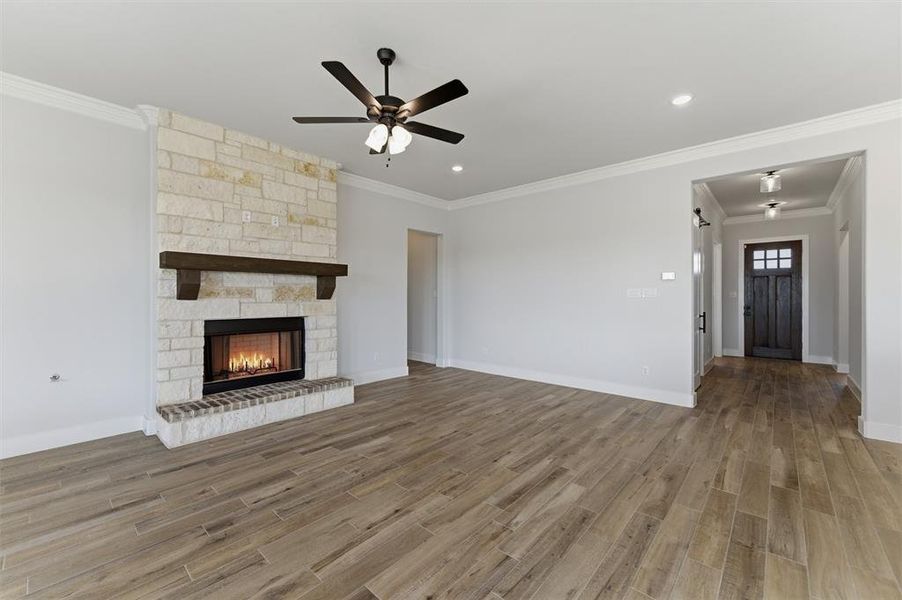 Unfurnished living room with ornamental molding, light wood finished floors, a fireplace, a ceiling fan, and recessed lighting