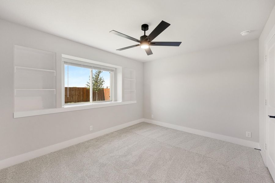 Empty bedroom with gray carpet, black ceiling fan, built-in wall shelves, and a single window Empty bedroom with gray carpet, black ceiling fan, built-in wall shelves, and a single window