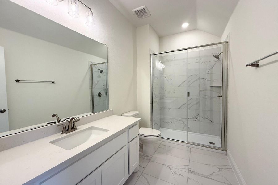 Bathroom featuring light marble finish flooring, vanity, and a marble finish shower