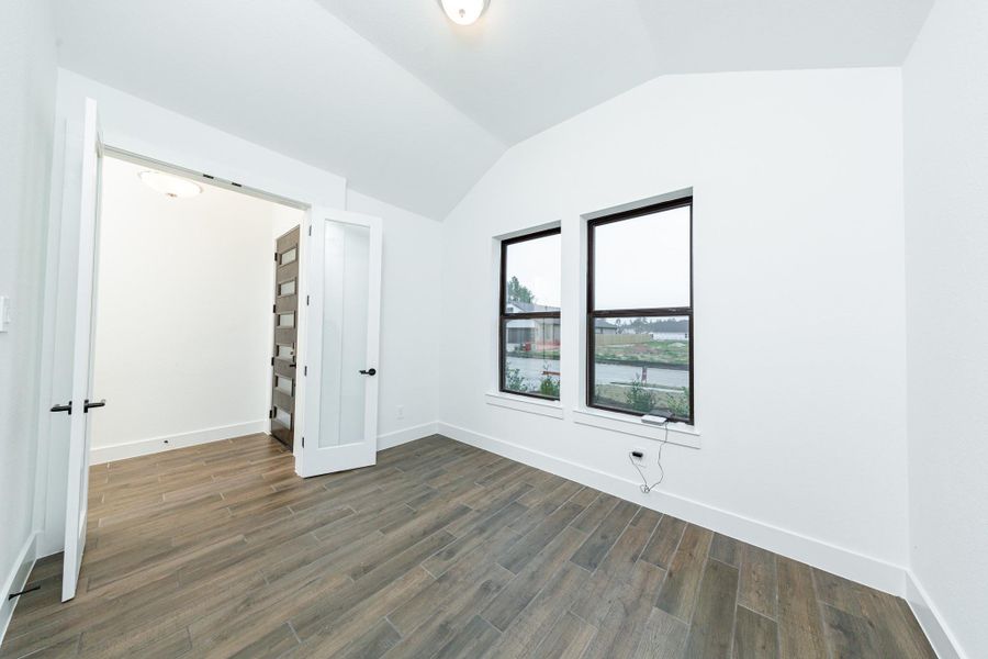 This handsome home office features tile flooring, large windows, cathedral ceilings, custom paint, walk-in closet, and gorgeous French doors for added privacy!