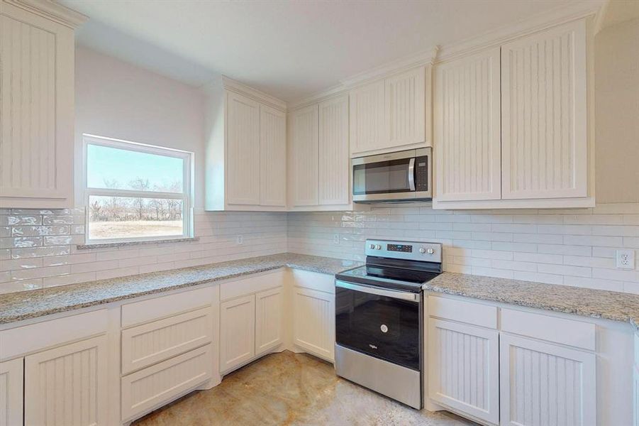 Kitchen featuring appliances with stainless steel finishes, backsplash, and light stone counters