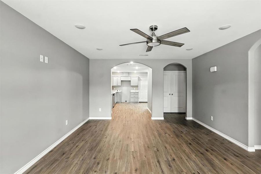 Unfurnished living room featuring ceiling fan, wood finished floors, and arched walkways Unfurnished living room featuring ceiling fan, wood finished floors, and arched walkways