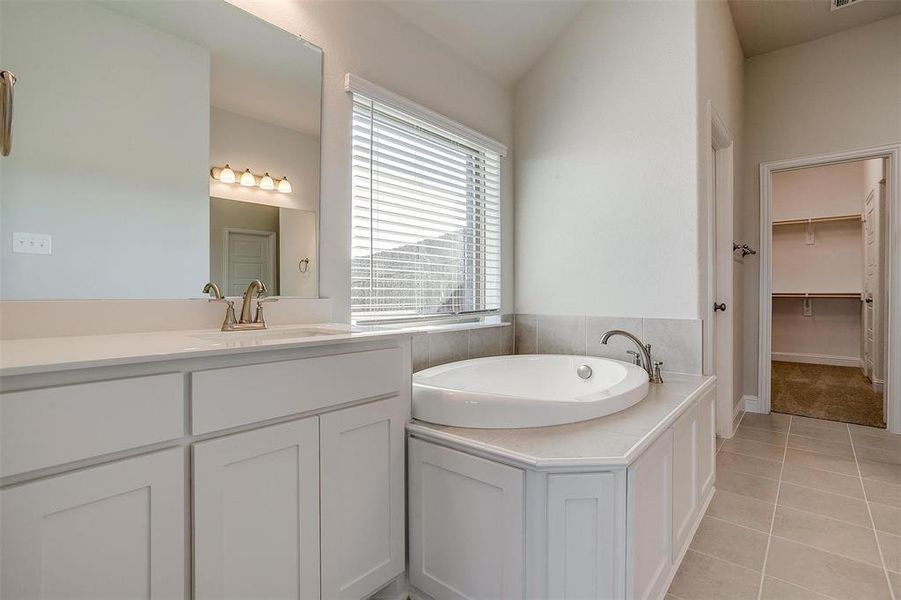 Bathroom featuring tile patterned floors, vanity, and a tub to relax in