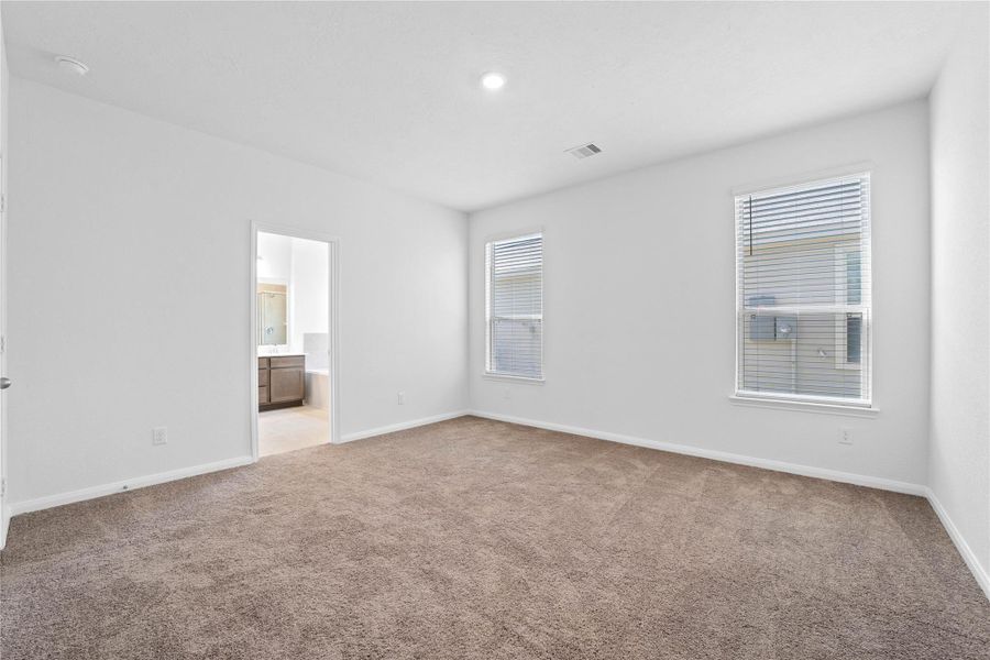 Relax and recharge in this stunning primary suite! Enjoy the comfort of plush carpeting, warm-toned walls, soaring ceilings, a ceiling fan for added comfort, and expansive windows with privacy blinds that fill the room with natural light.