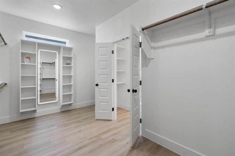 Walk in closet with light wood-type flooring Walk in closet with light wood-type flooring