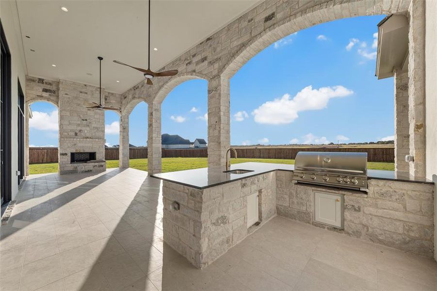 Fenced backyard with area for grilling, a patio, and an outdoor stone fireplace Fenced backyard with area for grilling, a patio, and an outdoor stone fireplace