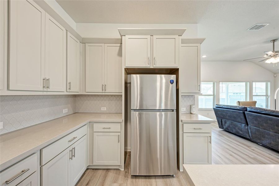 A well-appointed kitchen features ample cabinetry, gleaming stainless steel appliances, and a seamless flow into the sun-drenched living area.