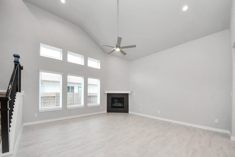Relax and unwind in this inviting family room, illuminated by abundant natural light streaming in through tall windows, complemented by high ceilings and stunning flooring. Stay comfortable year-round with the gentle breeze from the ceiling fan, creating the perfect atmosphere for family gatherings.