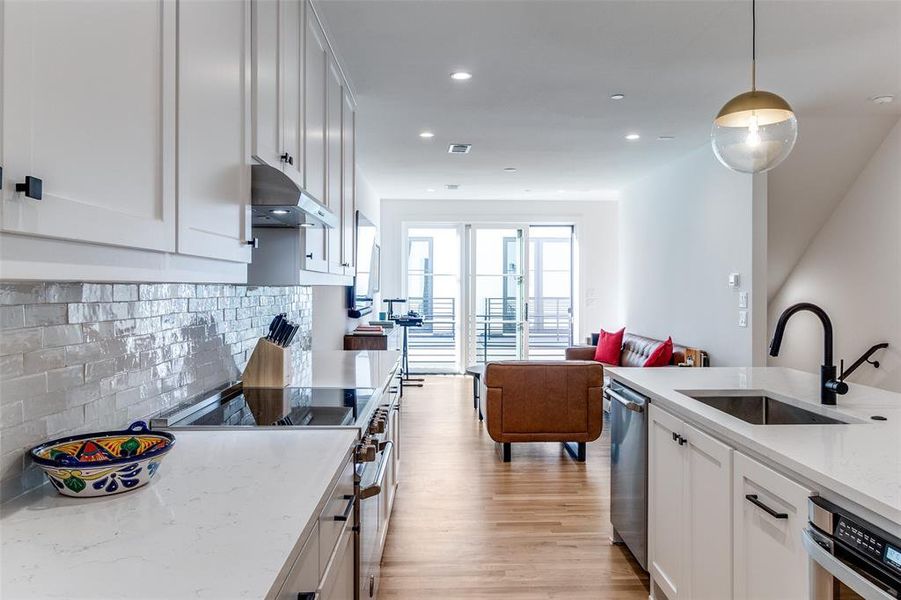 Kitchen featuring light stone countertops, white cabinets, stainless steel appliances, open floor plan, and backsplash Kitchen featuring light stone countertops, white cabinets, stainless steel appliances, open floor plan, and backsplash