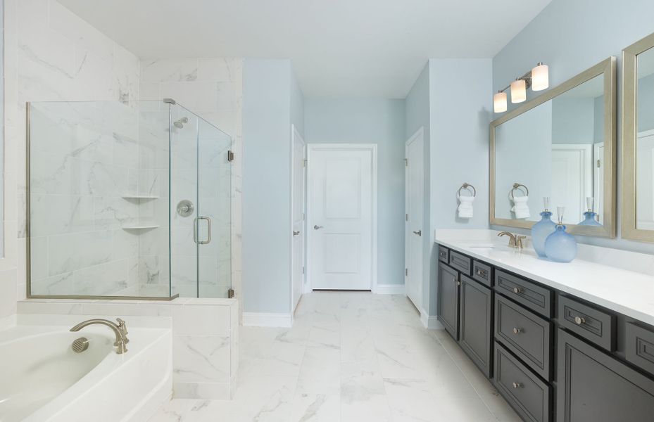 Beautiful owner's Bath equipped with framed mirrors and a frameless walk-in shower